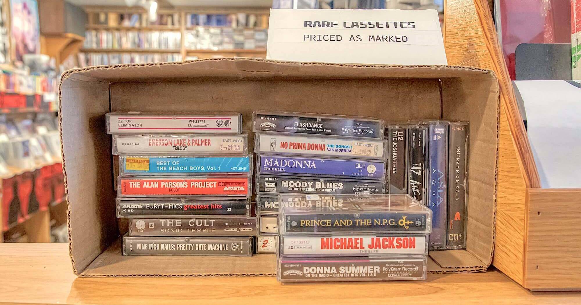 Аудиокассеты в ассортименте, лежащие на продажу в коробке на полке магазина