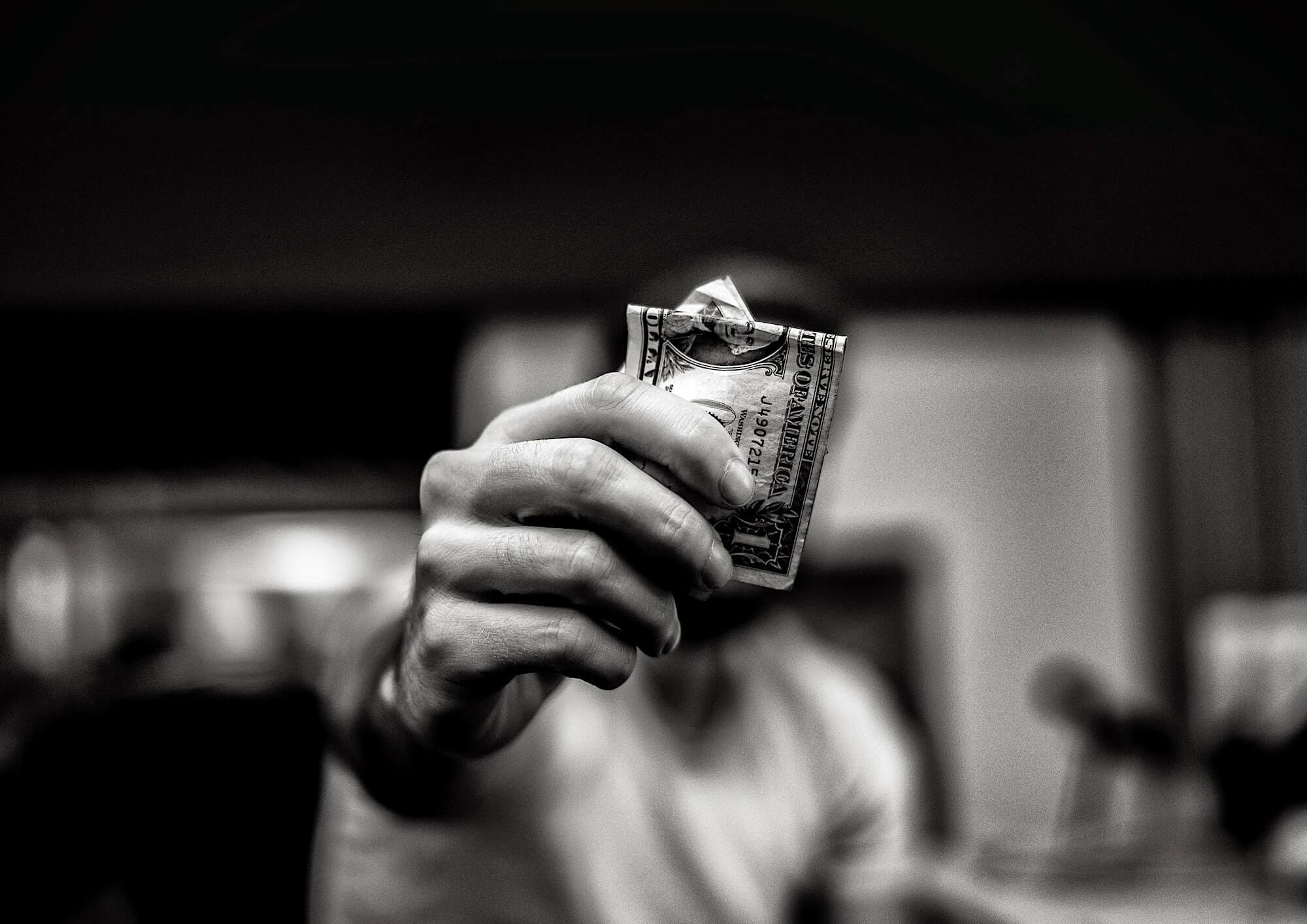Черно-белое фото смятой однодолларовой купюры в руках у мужчины
