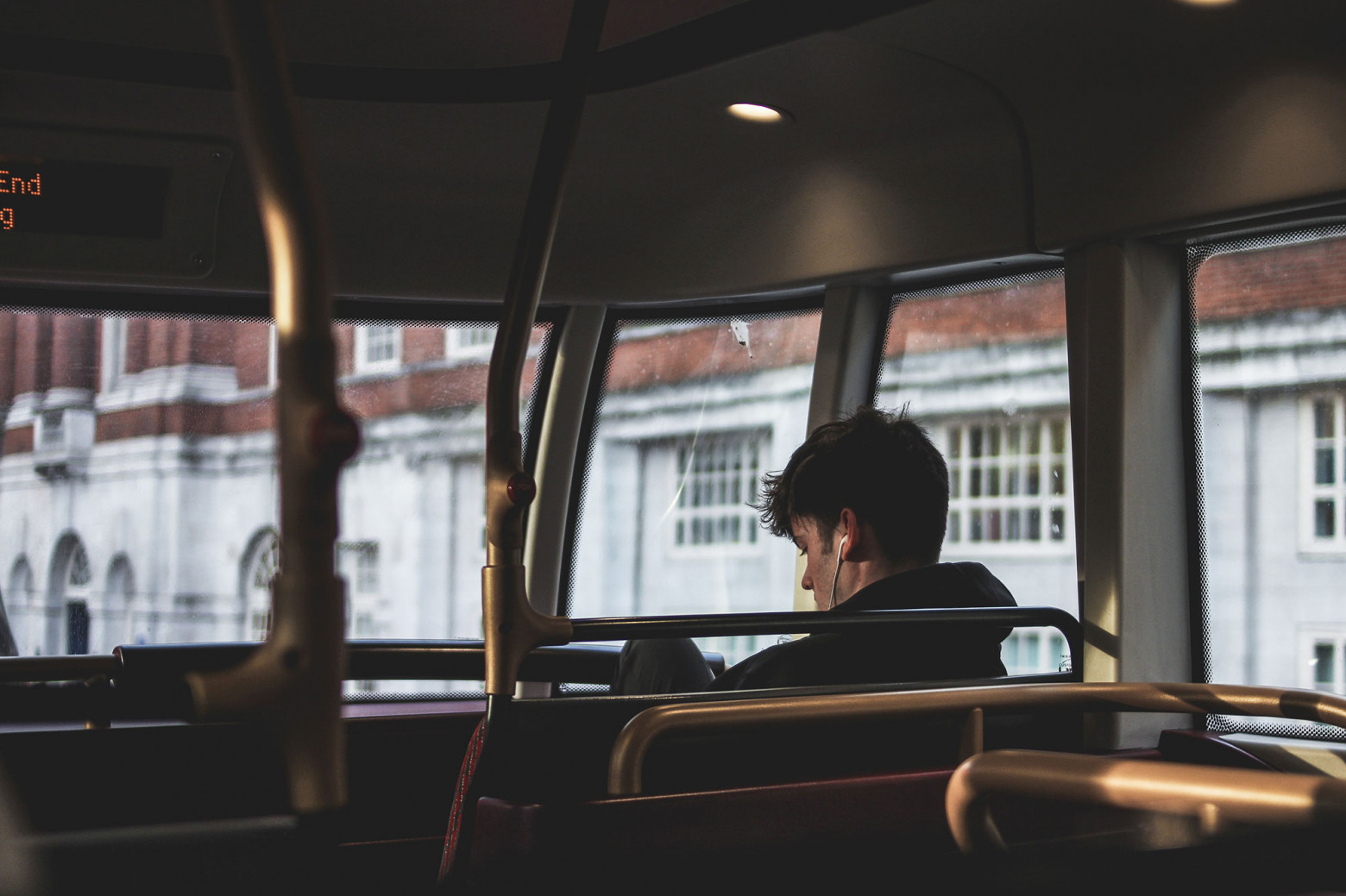 Парень в наушниках слушает музыку, сидя в одиночестве в наземном общественном транспорте
