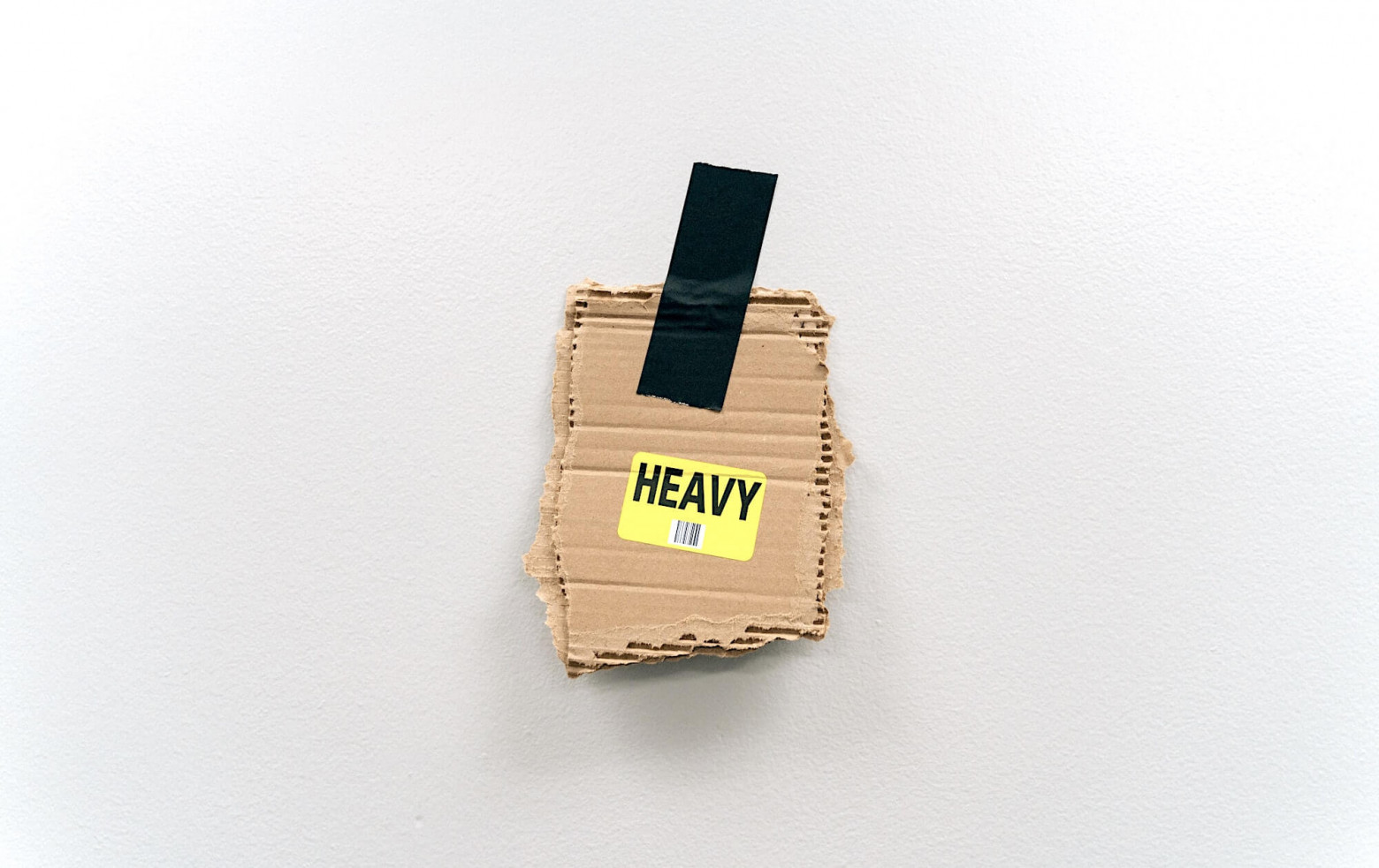 Картонка со словом «HEAVY», приклеенная к стене куском чёрной изоленты