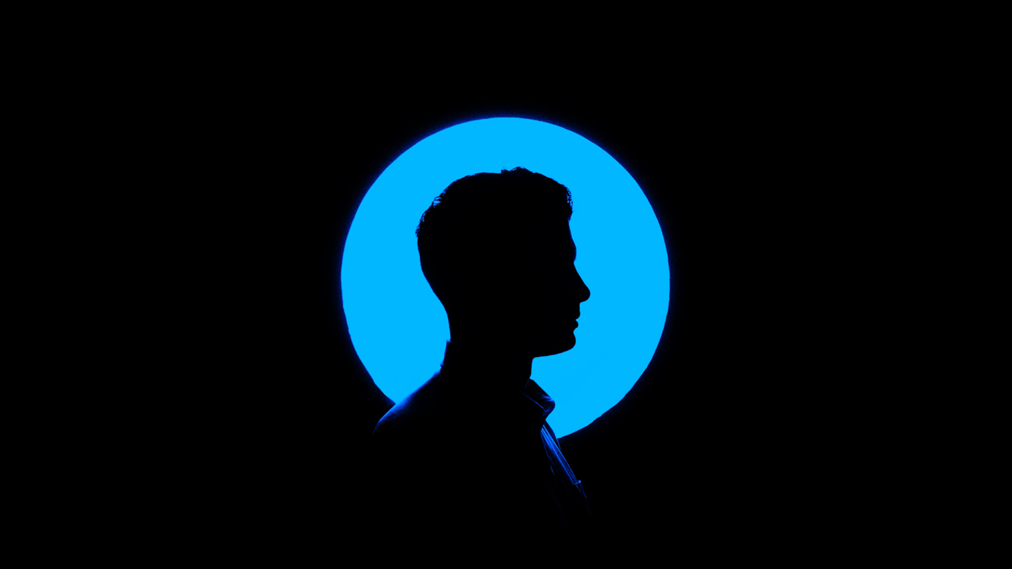 Силуэт мужчины в профиль на фоне синего круга в чёрном фоне