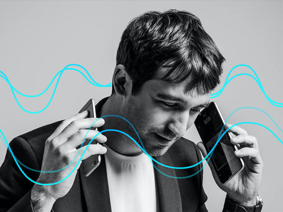 Мужчина с двумя смартфонами в руках слушает музыку