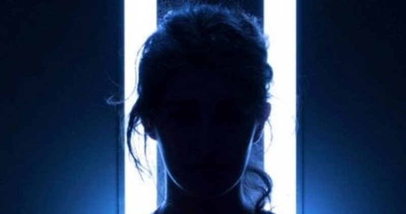 Лицо девушки в темноте, подсвеченное сзади двумя вертикальными лампами