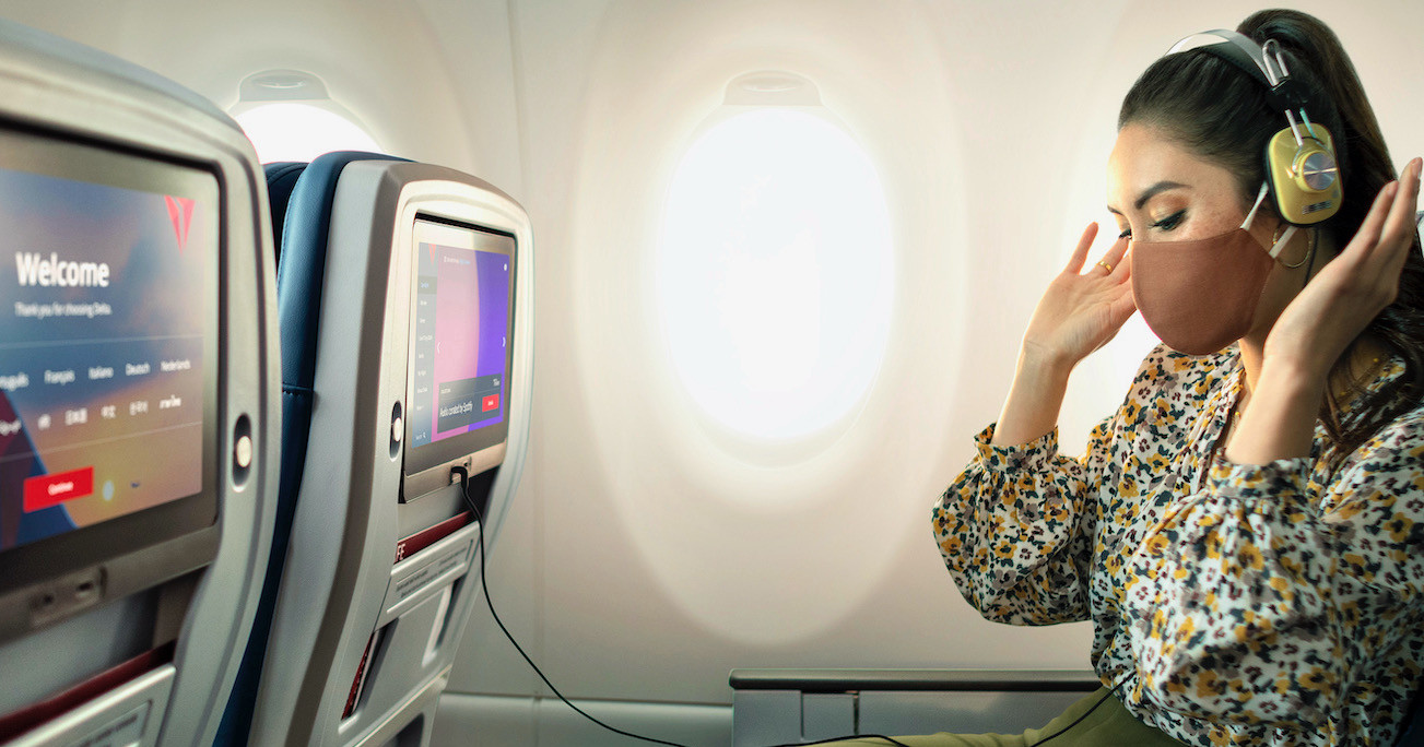 Жещина в наушниках слушает музыку на борту самолёта