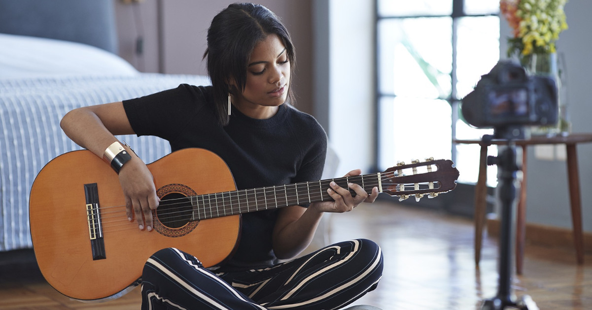 Индусская девушка играет на гитаре, сидя на полу в квартире